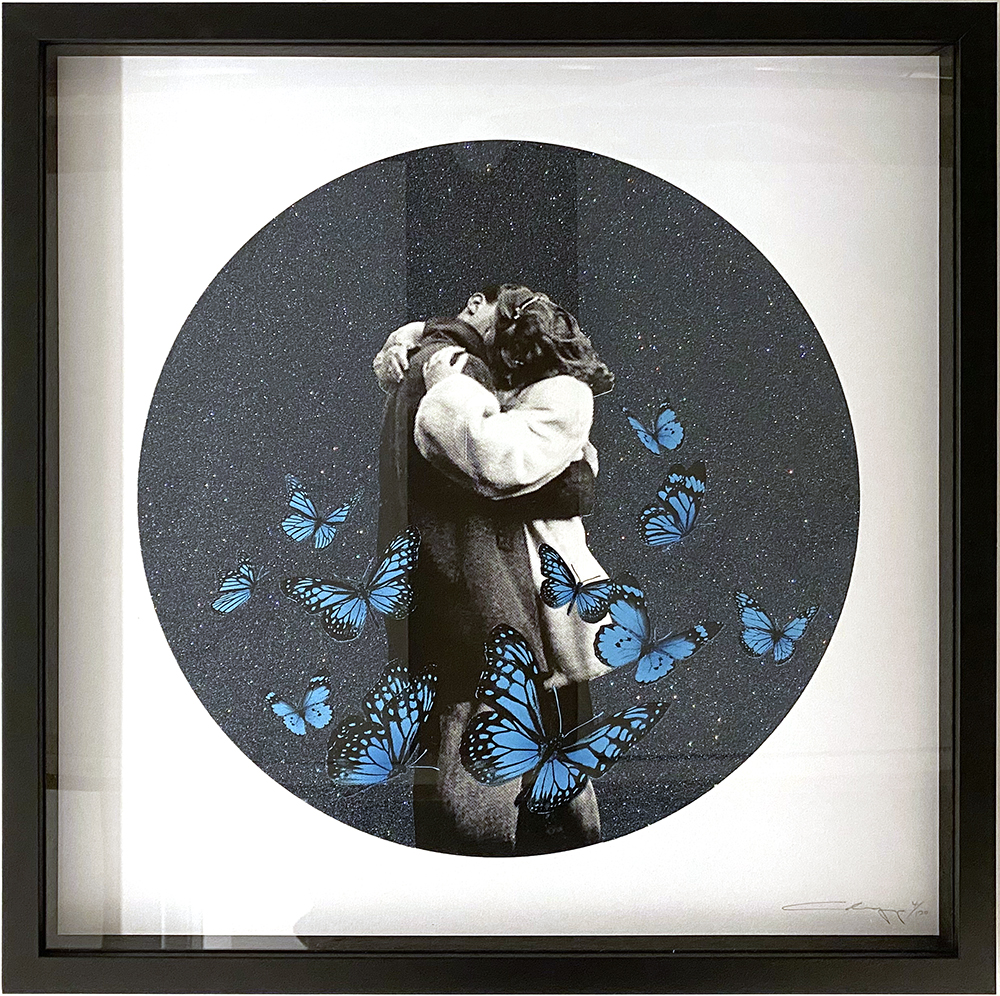 The piece, known as "Shut Up and Kiss Me - Starry Night Edition (Copy)," captures a tender moment of two individuals entwined in an embrace, all elegantly enclosed within a circular frame. This intimate scene is enriched by the presence of vivid blue butterflies that dance against a deep, dark backdrop, adding a splash of color and movement to the artwork's serene composition.