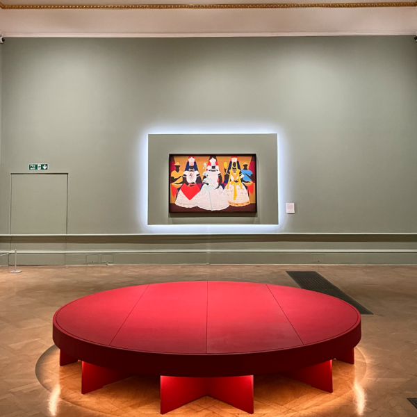 In a contemporary art gallery, a painting of vibrant figures is displayed under gentle lighting, embodying elements of Modernism. A substantial circular red platform complements the wooden flooring, adding to the ambience. The gallery's soft green walls create an intriguing backdrop, intensifying the painting's vivid colors, while a discreet exit sign quietly invites guests to move on.