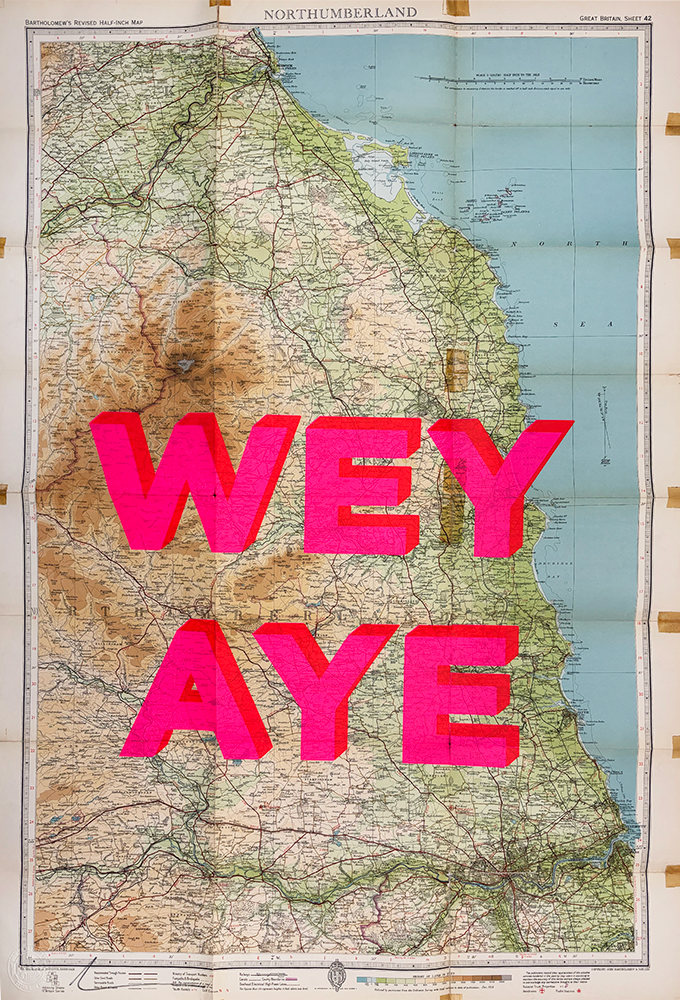 A captivating piece of art featuring a vintage map of Northumberland serves as the canvas, showcasing intricate geographical details, coastlines, and various locations within the region. Boldly overlaying this historic backdrop are large pink letters spelling out "WEY AYE," providing a striking contrast that fuses traditional cartography with modern pop art sensibilities.