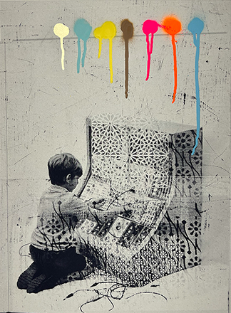 A child sits and plays with a patterned, geometric object; colorful paint drips from the top edge of the grayscale image.