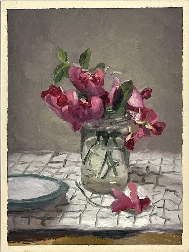 A glass jar filled with pink flowers sits on a chequered cloth next to a small plate, with one flower lying on the table.